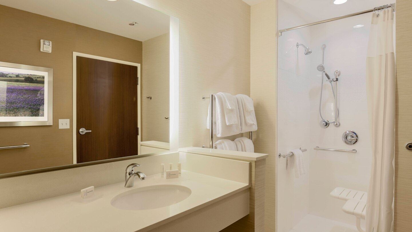 Modern guest bathroom with a large vanity and a roll in shower for easy wheel chair exessability