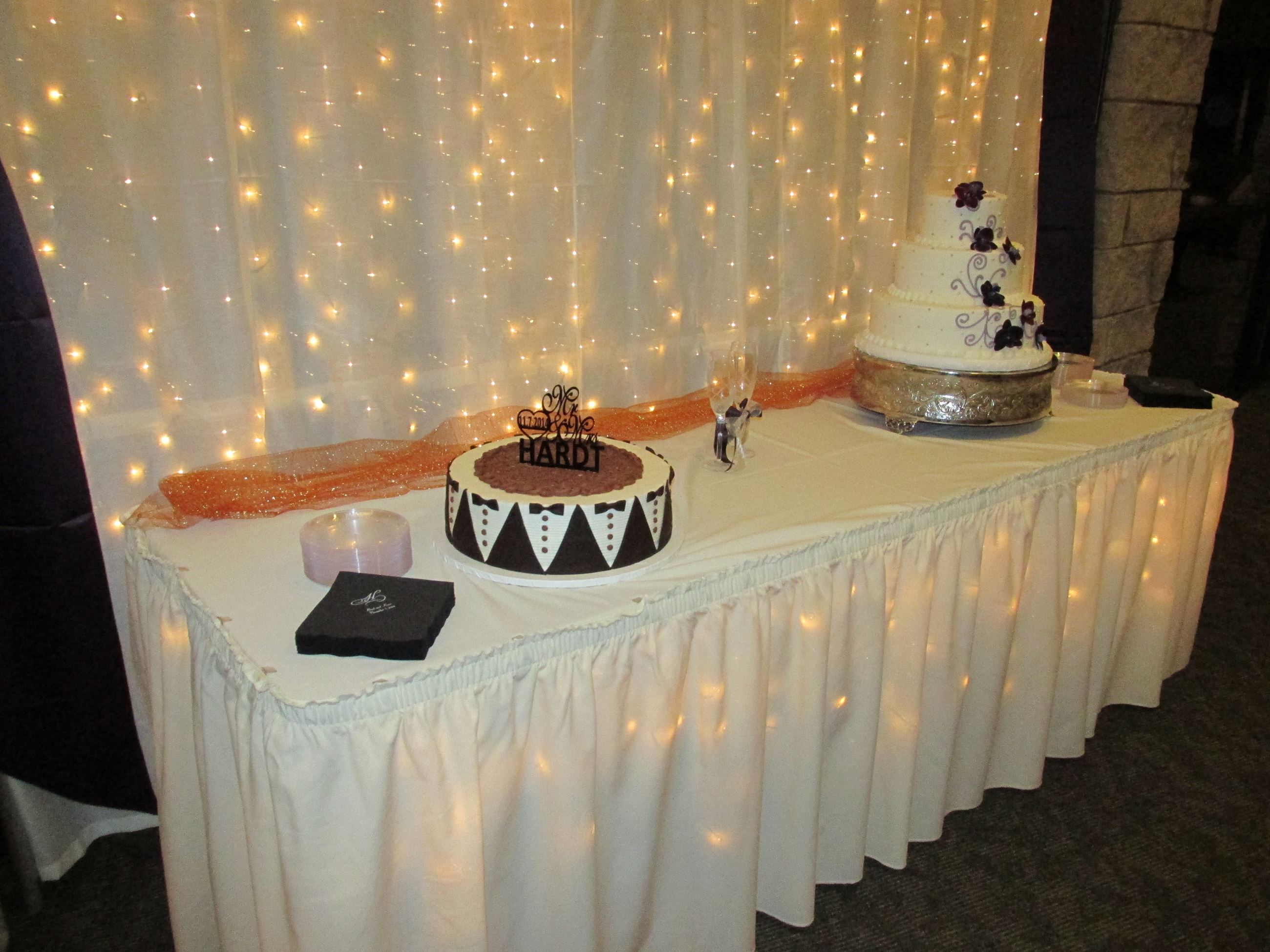 Small lighted cake table with wedding cake and groom cake in the Chisholm Suites